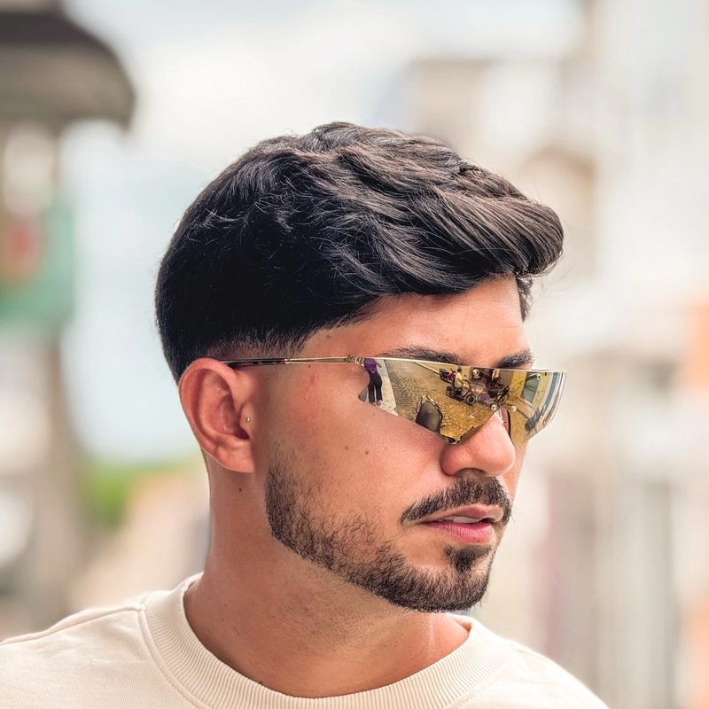 Cliente usando óculos de sol de lente única dourada espelhada, olhando de perfil, fundo externo desfocado